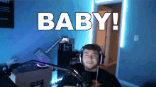 a man wearing headphones is sitting in front of a microphone and the word baby is on the screen