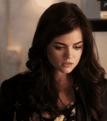 a close up of a woman 's face with long dark hair and a black jacket .
