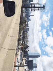 a rear view mirror shows a city skyline with a large billboard in the foreground