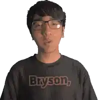 a man wearing glasses and a bryson shirt smiles for the camera