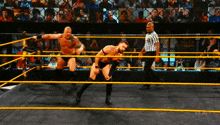 two men are wrestling in a ring with the word nxt on the bottom right