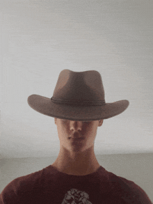 a young man wearing a brown cowboy hat