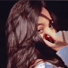 a girl with long hair is covering her mouth with her hand