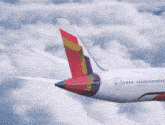 a white airplane with a red yellow and blue tail is flying in the clouds