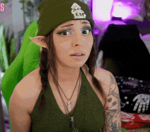 a woman wearing a green beanie with a logo that says s on it
