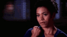 a close up of a woman 's face in a dark room with a fist in her hand .