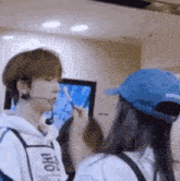 a man wearing a microphone is talking to a woman wearing a blue hat