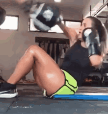 a woman wearing boxing gloves is sitting on the floor