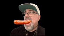 a man with a beard wearing glasses and a hat is eating a sausage