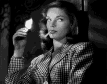 a black and white photo of a woman lighting a cigarette .