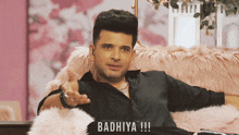 a man in a black shirt is sitting in a chair with the words badhiya written on the bottom right