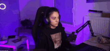 a woman wearing headphones is sitting at a desk with a laptop and microphone .
