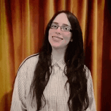 the woman is wearing glasses and a striped shirt and smiling .