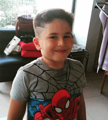 a young boy wearing a spider man t-shirt smiles for the camera