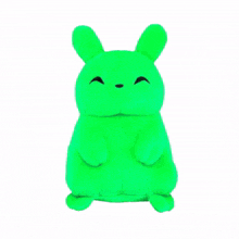 a green stuffed animal with a glow in the dark face is sitting on a white surface .