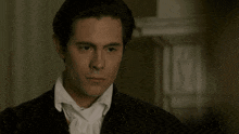 a man wearing a black jacket and a white shirt is looking at the camera