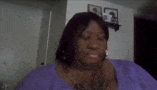 a woman in a purple shirt is sitting in a living room with her eyes closed