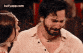 a man with a beard is crying while a woman looks at him .