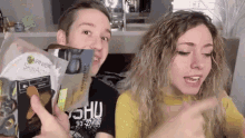 a man and a woman are standing next to each other holding a bag of garnier skinactives .