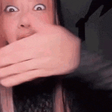 a woman is covering her mouth with her hands and making a funny face .