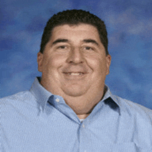 a man in a blue striped shirt is smiling for the camera
