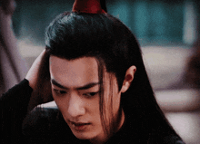 a man with long black hair and a red hat on his head