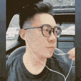 a man wearing glasses and ear buds looks to his left