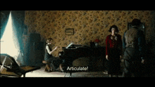 a man and a woman are standing in a room with a woman playing a piano and the words articulate on the screen .