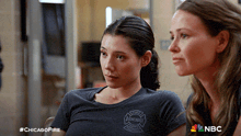 two women are sitting next to each other with a chicago fire logo on their shirts
