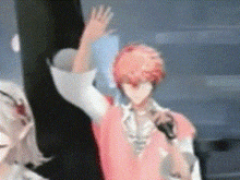a man with red hair is holding a microphone and waving while standing next to a woman .