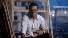 a man in a white shirt holds a bag of popcorn in his hand