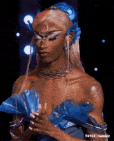 a woman wearing a blue dress and a necklace with the hashtag t4yce on the bottom right
