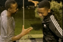 two boys are standing next to each other and one is wearing a black adidas jacket