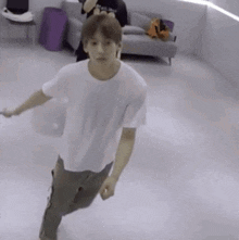 a young man in a white t-shirt and khaki pants is dancing on a white floor .