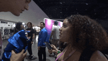 a woman with curly hair is talking to a man in front of a sign that says ' san diego ' on it