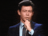 a man in a suit is singing into a microphone .