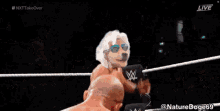 two men are wrestling in a wrestling ring while a referee watches .