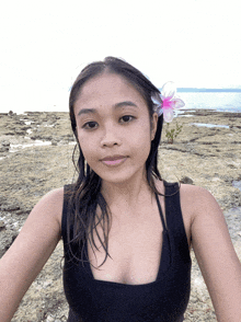 a woman wearing a flower in her hair looks at the camera