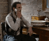 a man talking on a cell phone in front of a sink