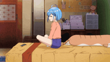 a girl with blue hair sits on a bed with a cat on it