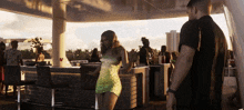 a woman in a green dress is dancing in front of a man in a black shirt