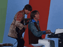 a man playing a guitar and another man playing a piano