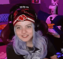 a girl with purple hair is wearing headphones and a headband with an akatsuki symbol on it .