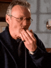 a man with glasses and a ring on his finger is covering his mouth