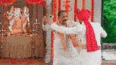 two men are standing next to each other in front of a temple taking a selfie with a cell phone .