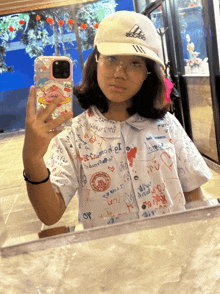a girl wearing a white adidas hat takes a picture of herself in the mirror