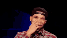 a man in a plaid shirt and hat is laughing