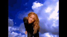 a woman is standing in front of a cloudy sky