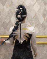 a woman with blue hair and white feathers in her braid