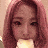 a close up of a woman with pink hair eating a piece of cake .